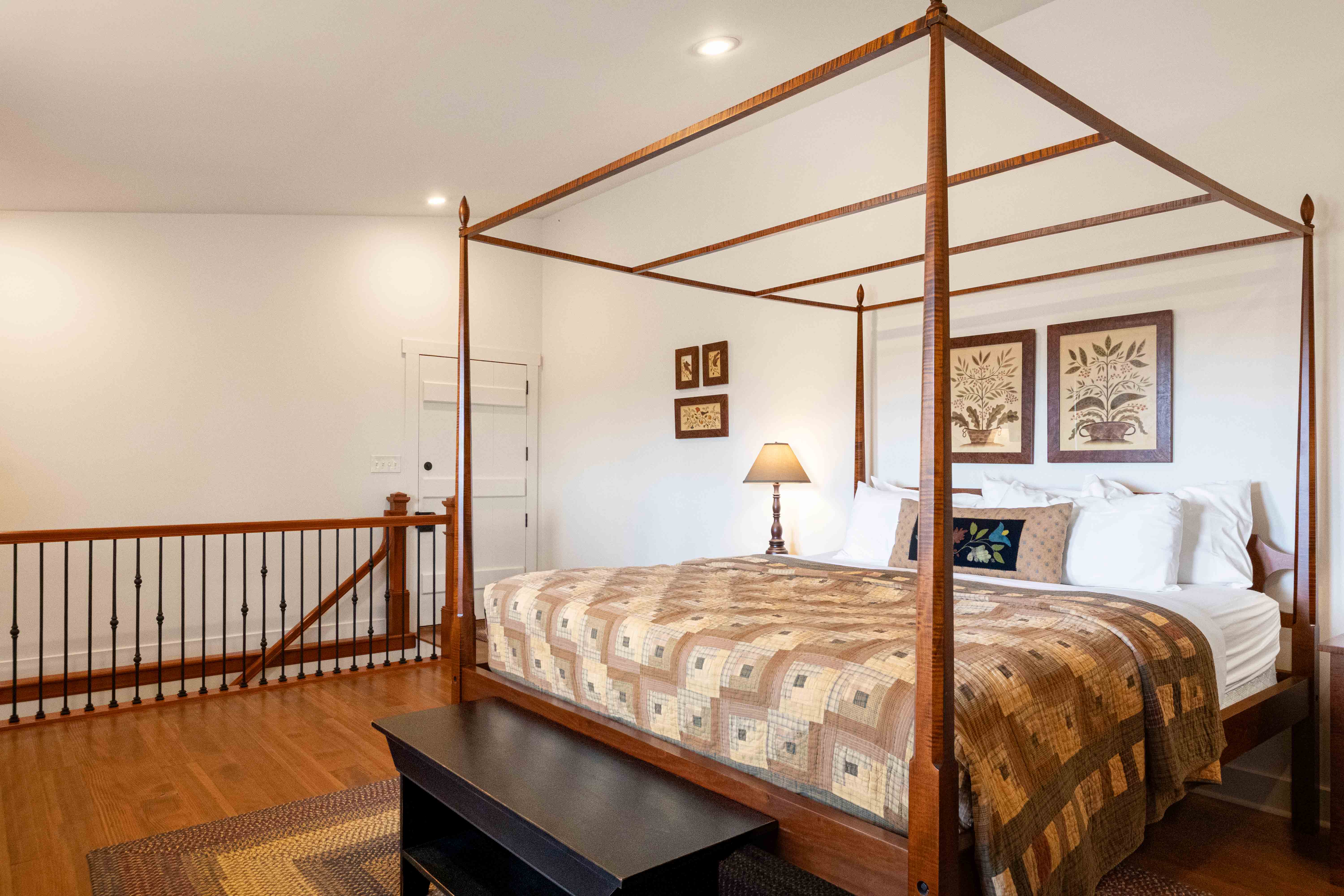 A cozy bedroom featuring a four-poster bed, wooden flooring, and decorative wall art.