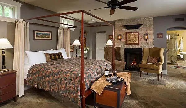 A cozy bedroom featuring a four-poster bed, a fireplace, and comfortable seating.