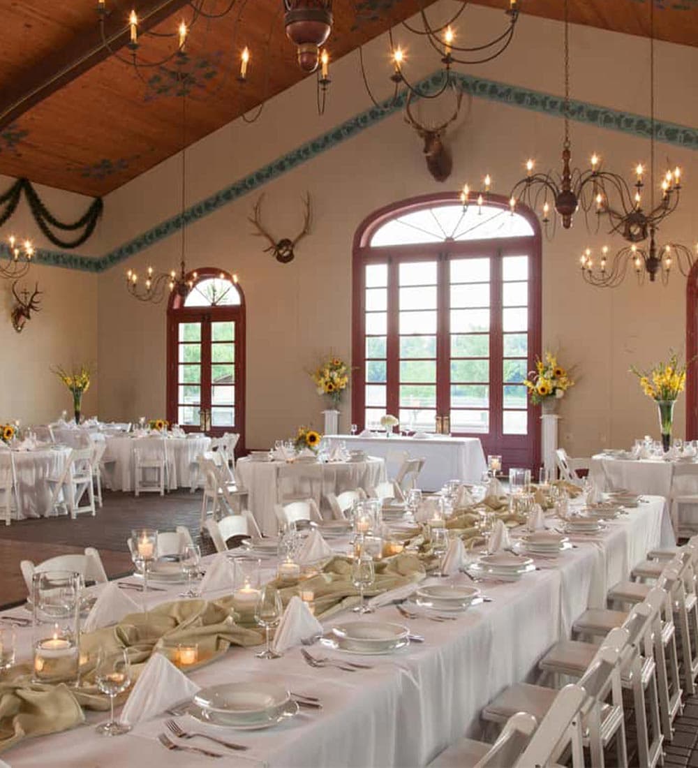 A beautifully decorated banquet hall with tables set for dining, featuring elegant centerpieces and warm lighting.