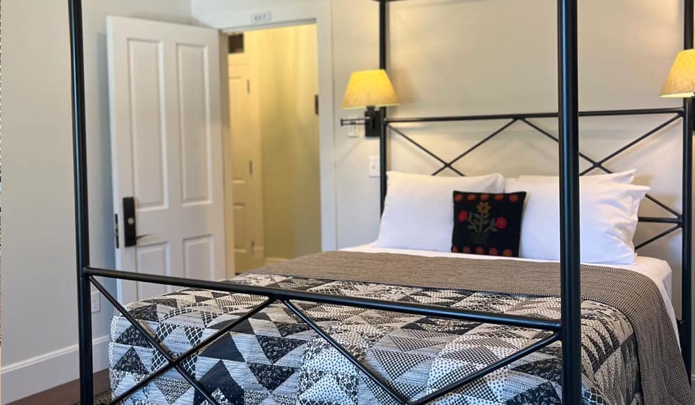 A cozy bedroom featuring a modern metal canopy bed, soft white linens, and warm lighting.