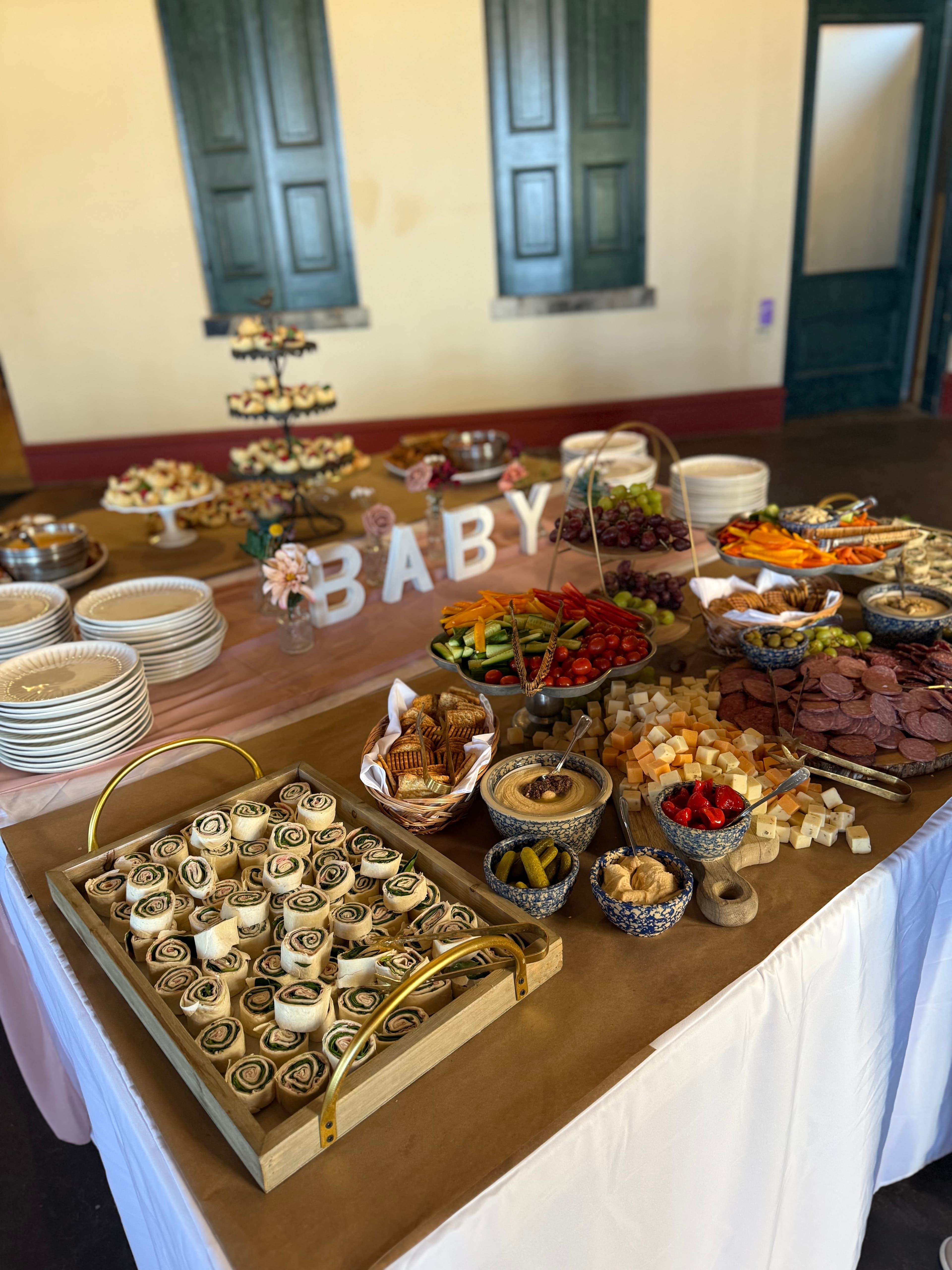 A beautifully arranged buffet table featuring a variety of appetizers, fruits, and desserts with a "BABY" sign in the background.