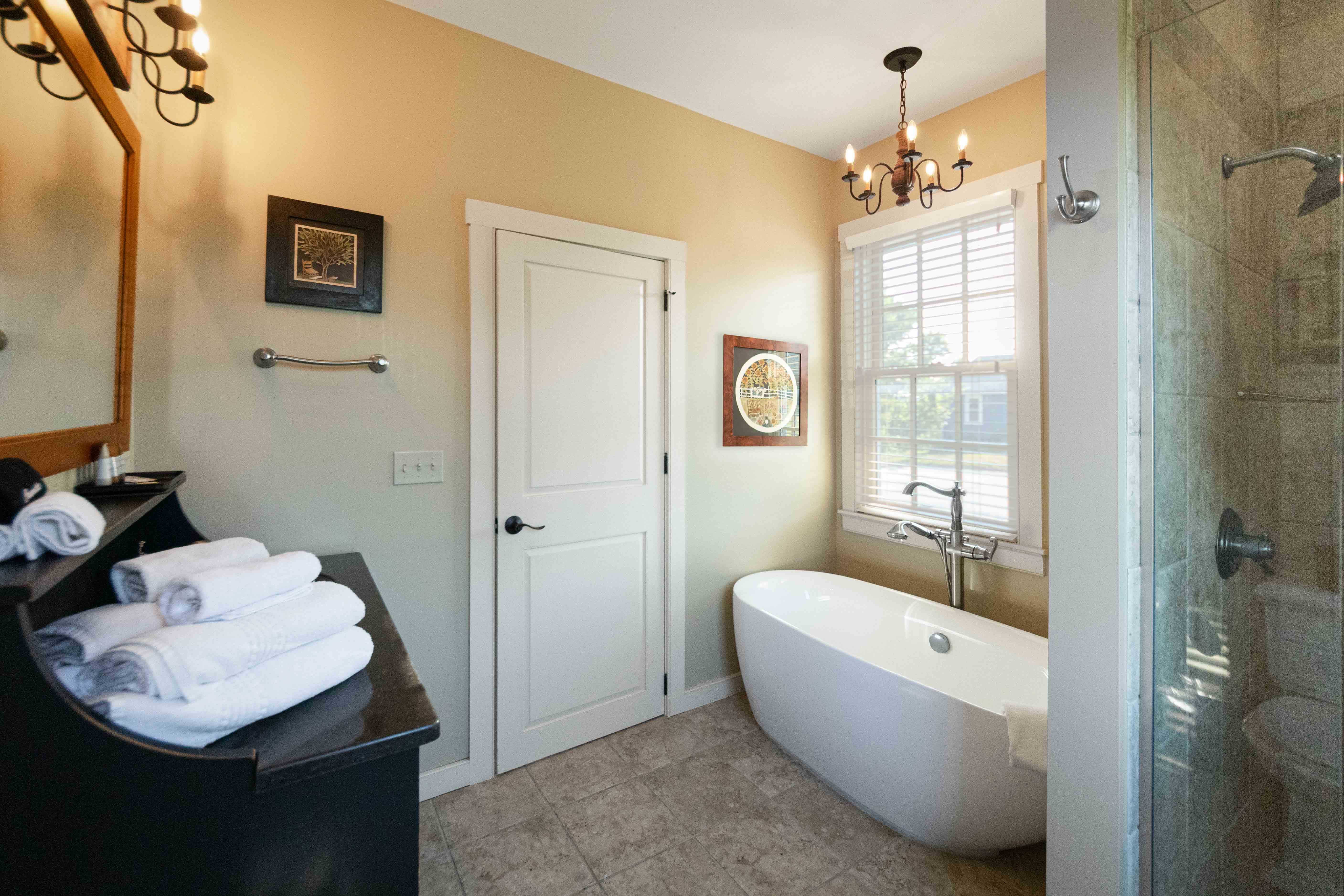 A modern bathroom featuring a freestanding tub, vanity with towels, and natural light from a window.
