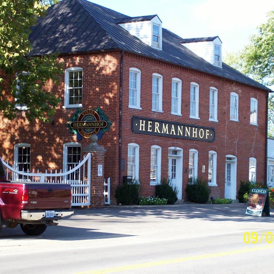 A brick winery building with the sign "Hermannhof" and a closed sign out front.