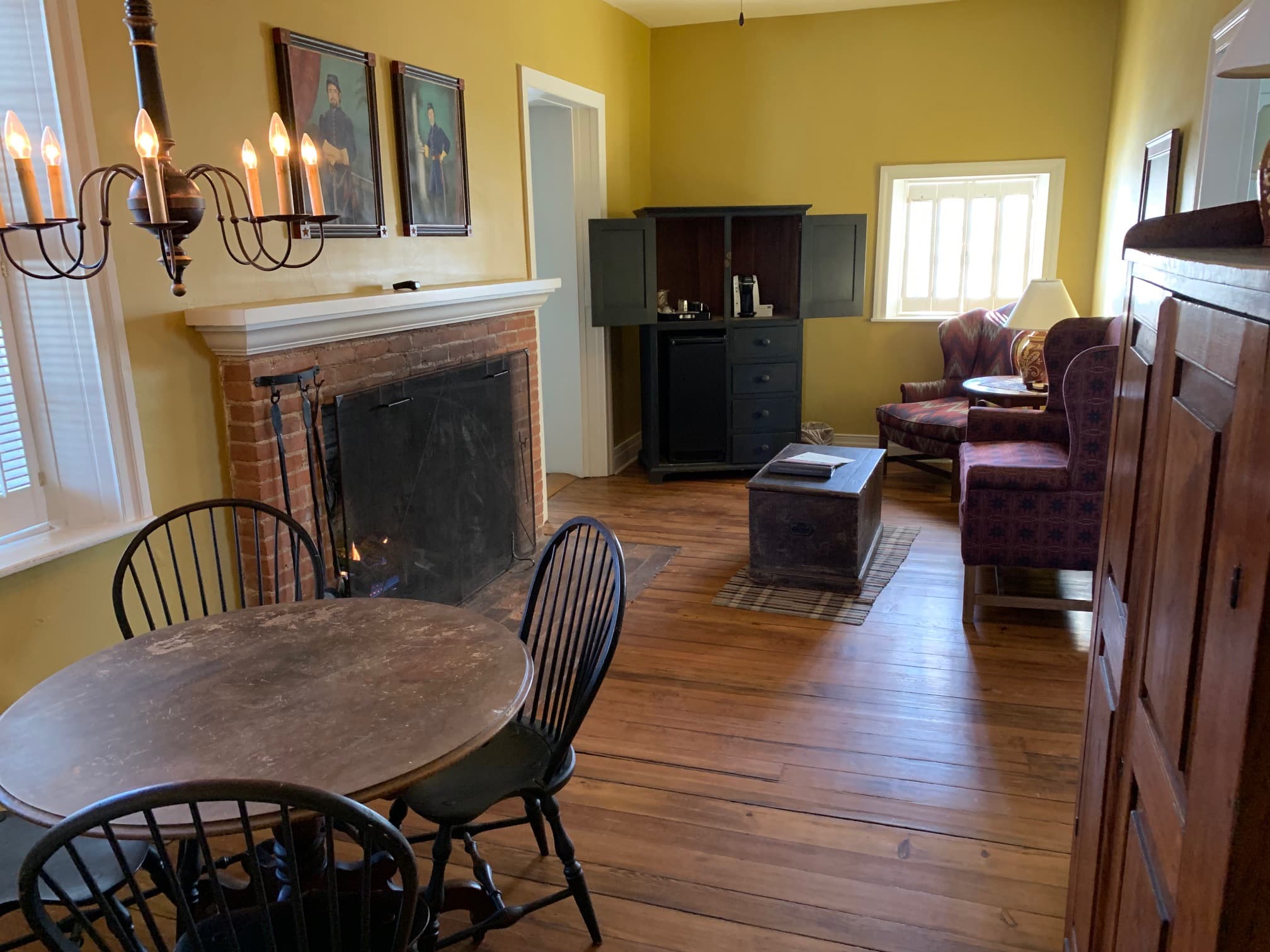 A cozy living space with a fireplace, a dining table, and a plush armchair.