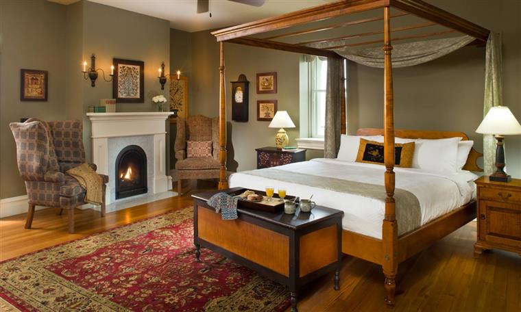 Elegant bedroom featuring a four-poster bed, cozy seating, and a fireplace.