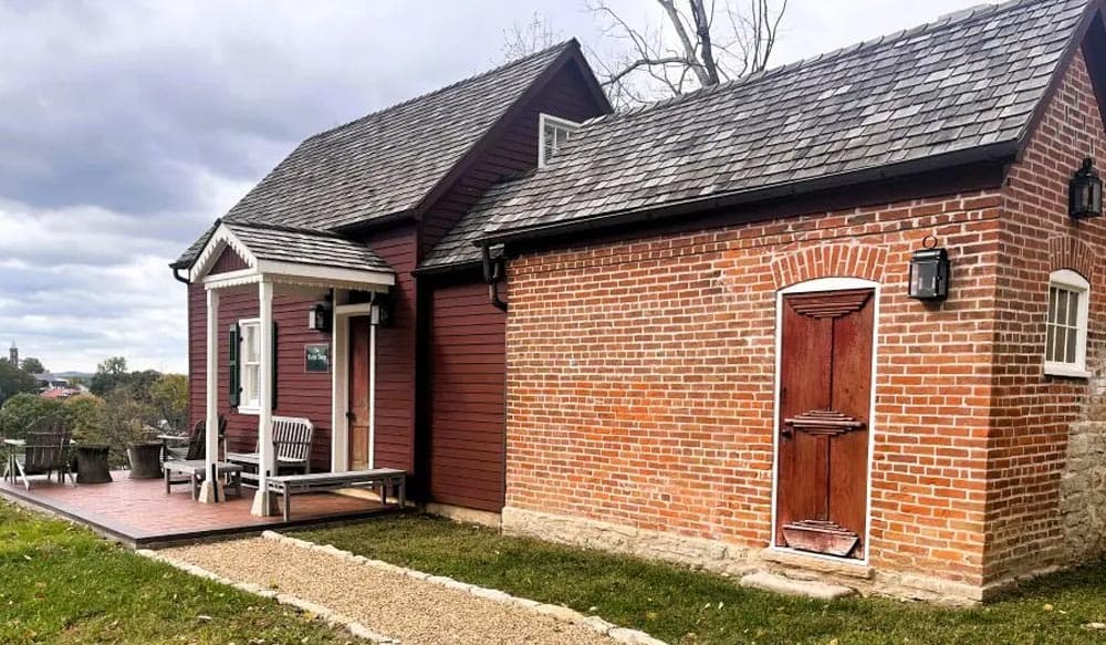 A charming house featuring a combination of wood and brick exteriors with a small porch.