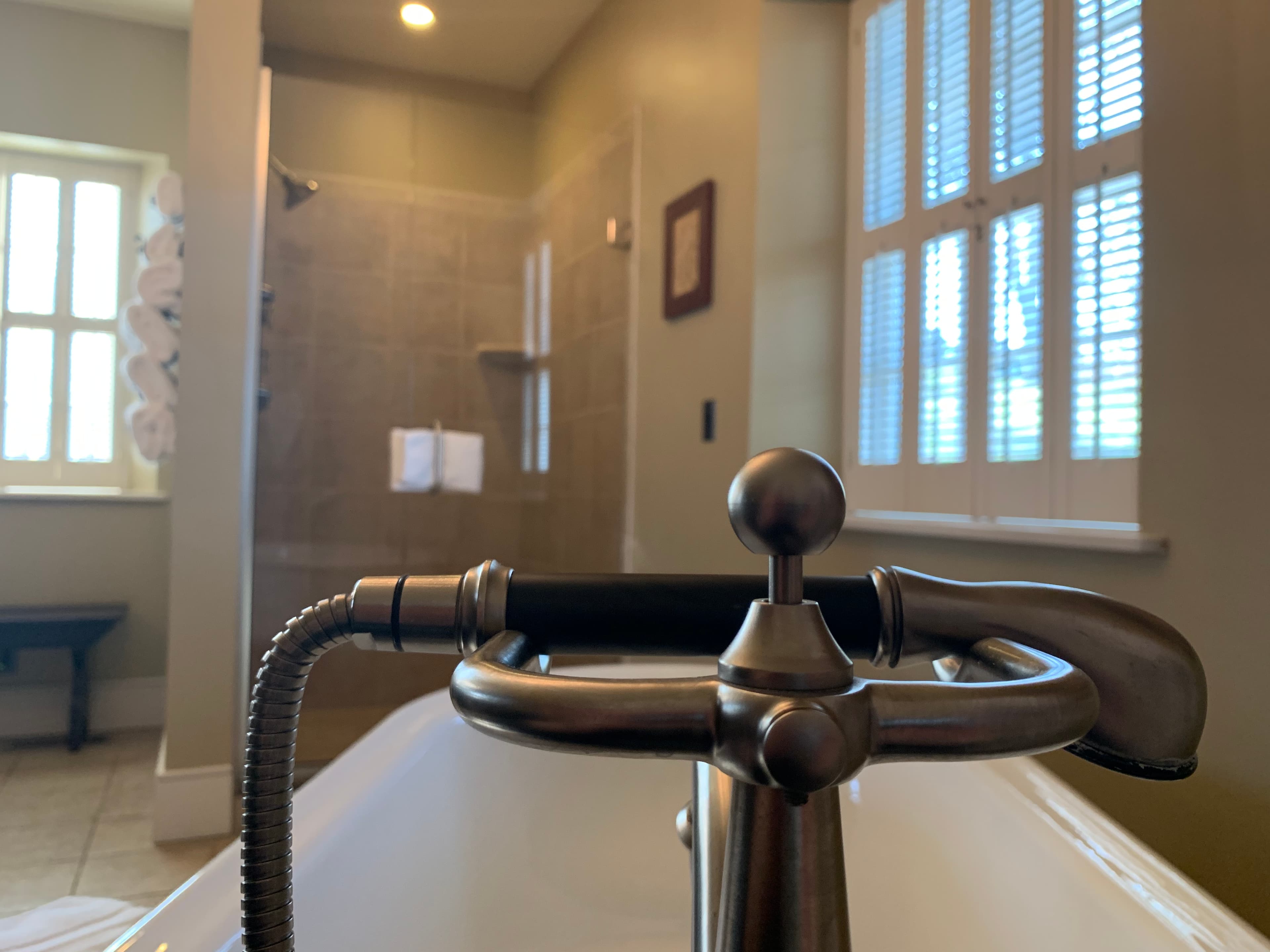 A close-up of a stylish bathtub faucet with a serene bathroom interior in the background.