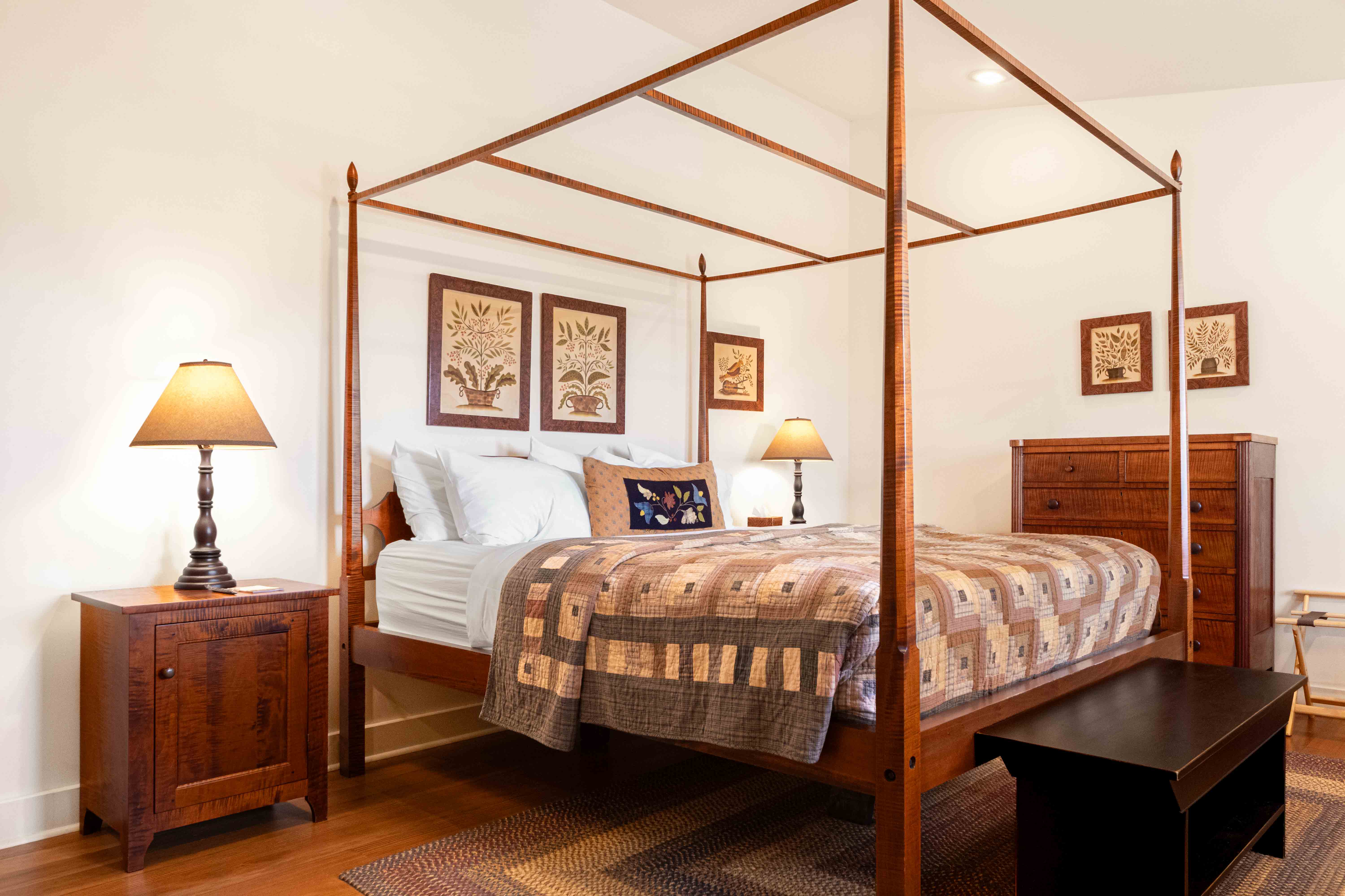 A cozy bedroom featuring a four-poster bed, warm lighting, and decorative artwork on the walls.