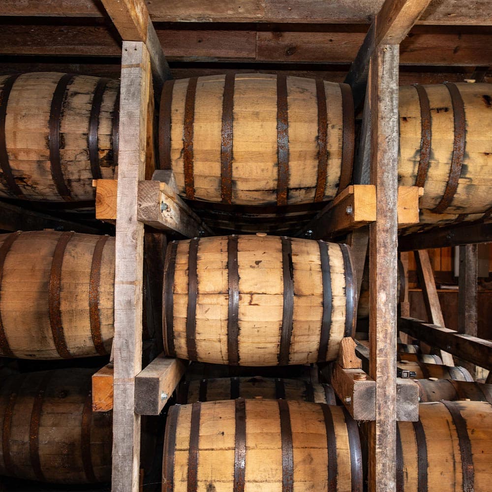 A stack of wooden barrels stored on shelving in a rustic setting.