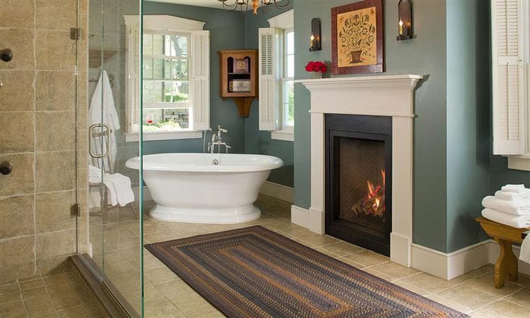 A serene bathroom featuring a freestanding bathtub, a glass shower, and a cozy fireplace.