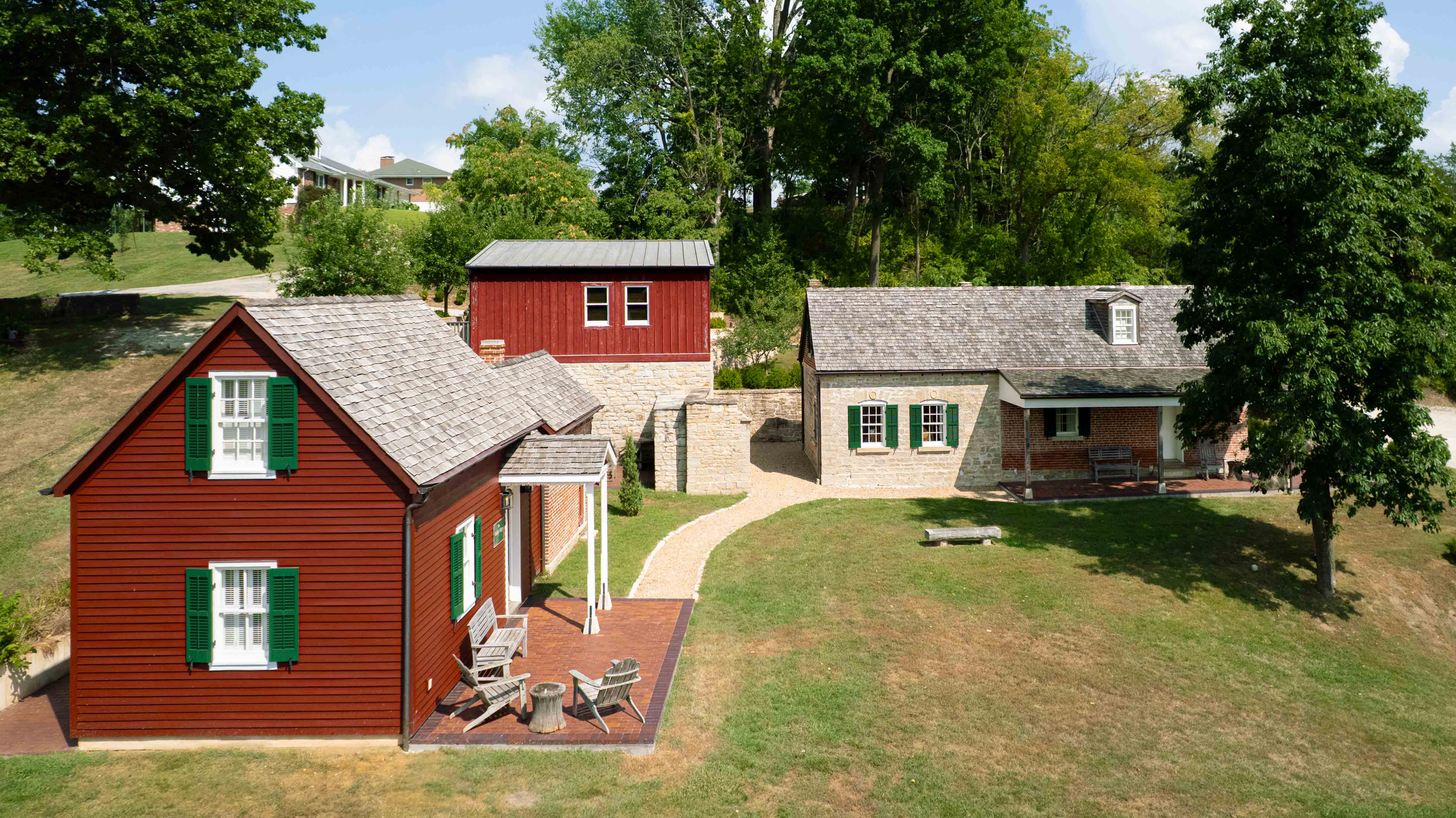 Aerial view of two rustic homes with green shutters and a landscaped yard.