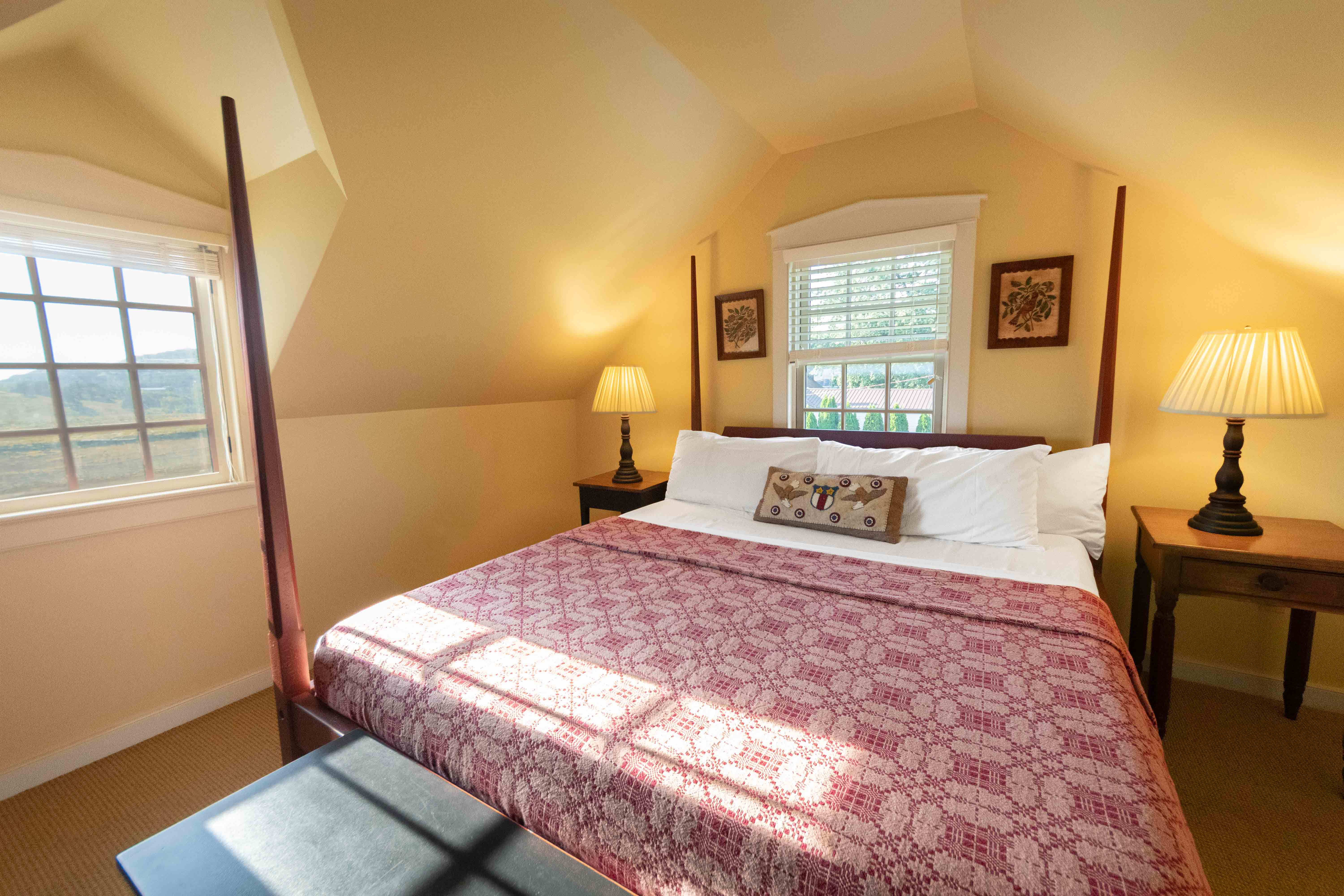 Cozy bedroom with a patterned blanket, two lamps, and natural light from a window.