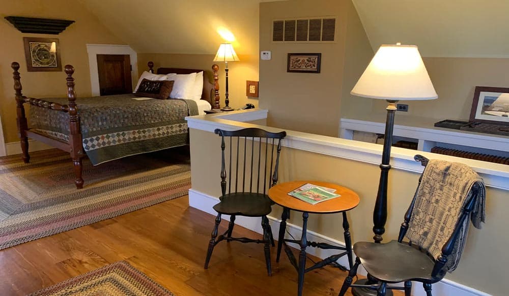 A cozy bedroom with a quilted bed, wooden furniture, and soft lighting.
