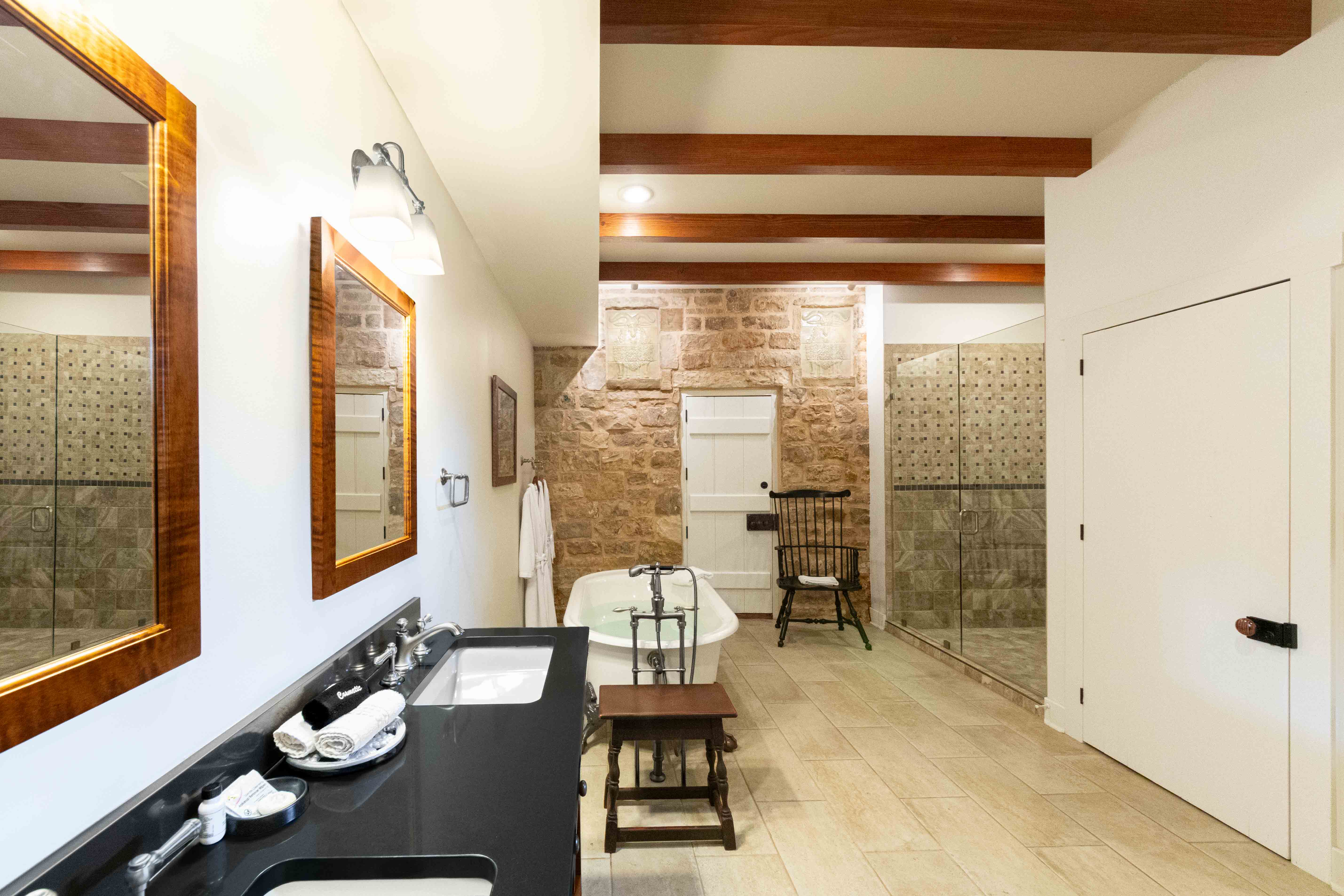 Modern bathroom with stone walls, double vanity, shower, and a bathtub.