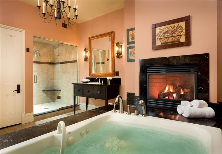 Luxurious bathroom featuring a jacuzzi, fireplace, and shower area with elegant decor.