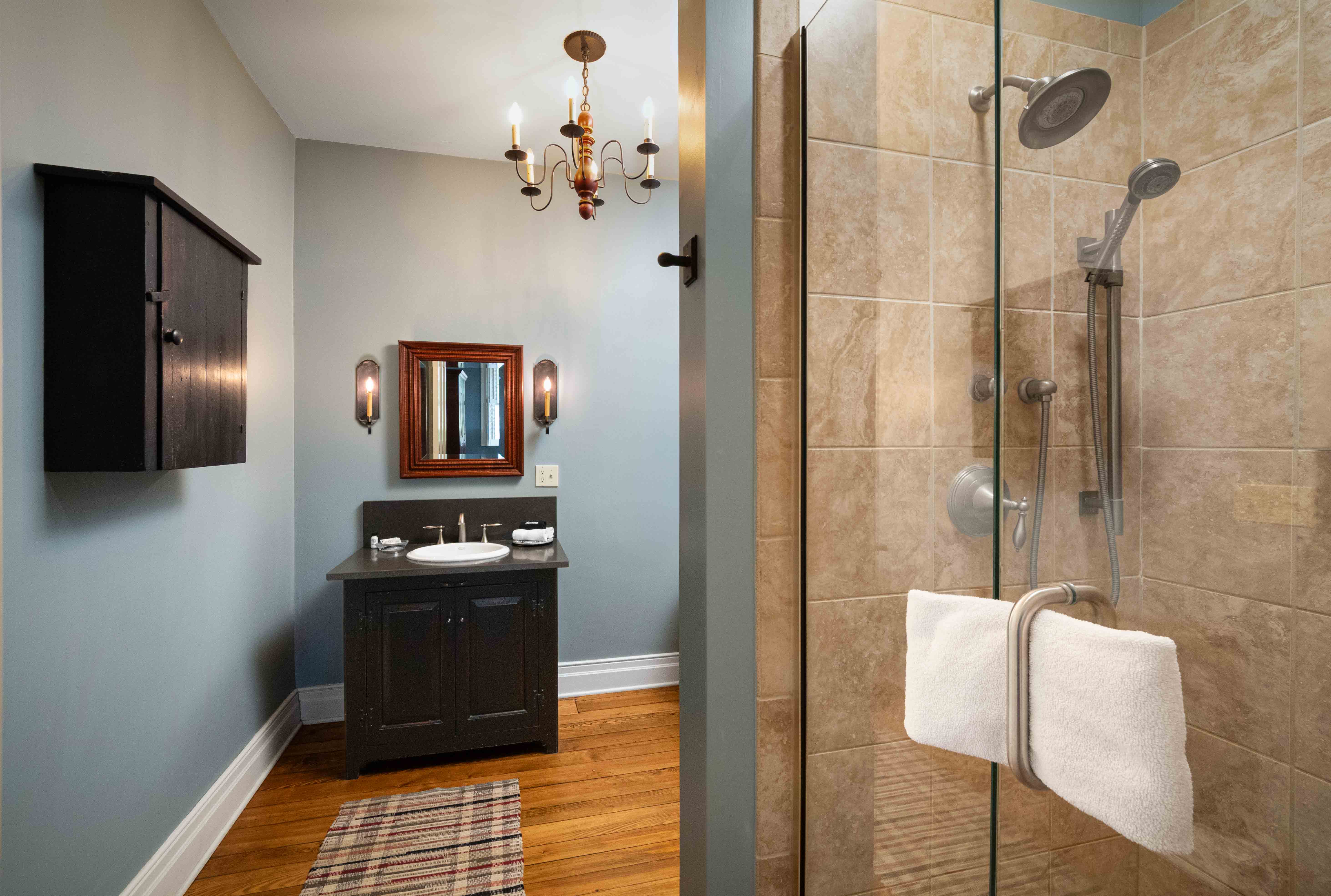 A modern bathroom featuring a glass shower, black vanity, and elegant lighting.
