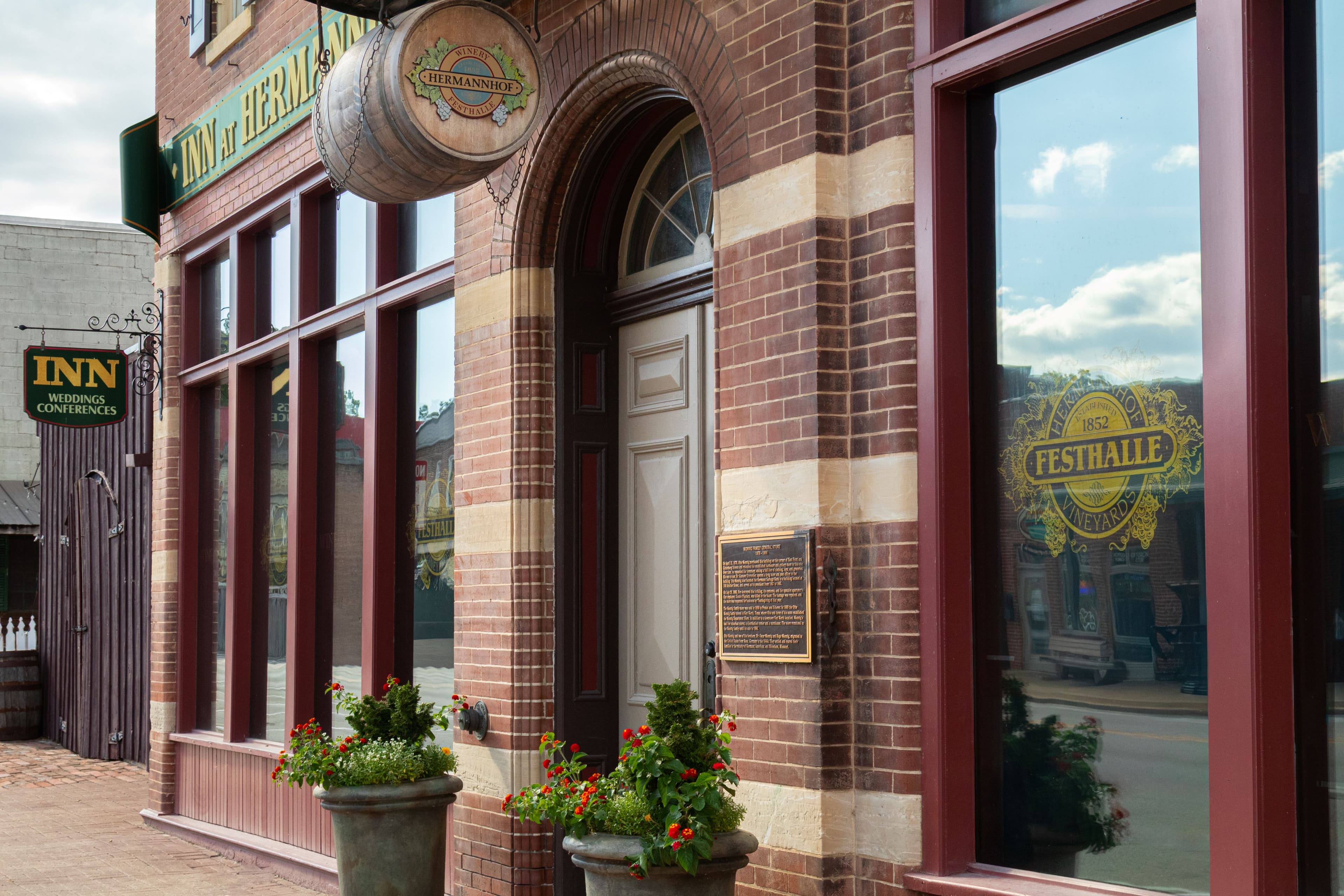 Brick facade of an inn with flower pots and large windows.