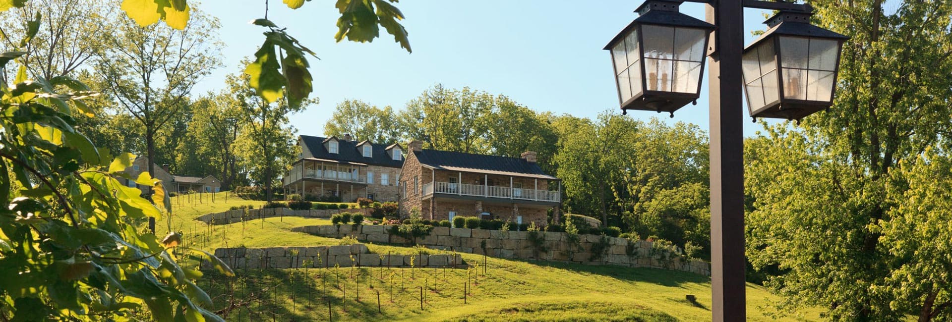 A scenic hillside view featuring a large house and lanterns among lush greenery.