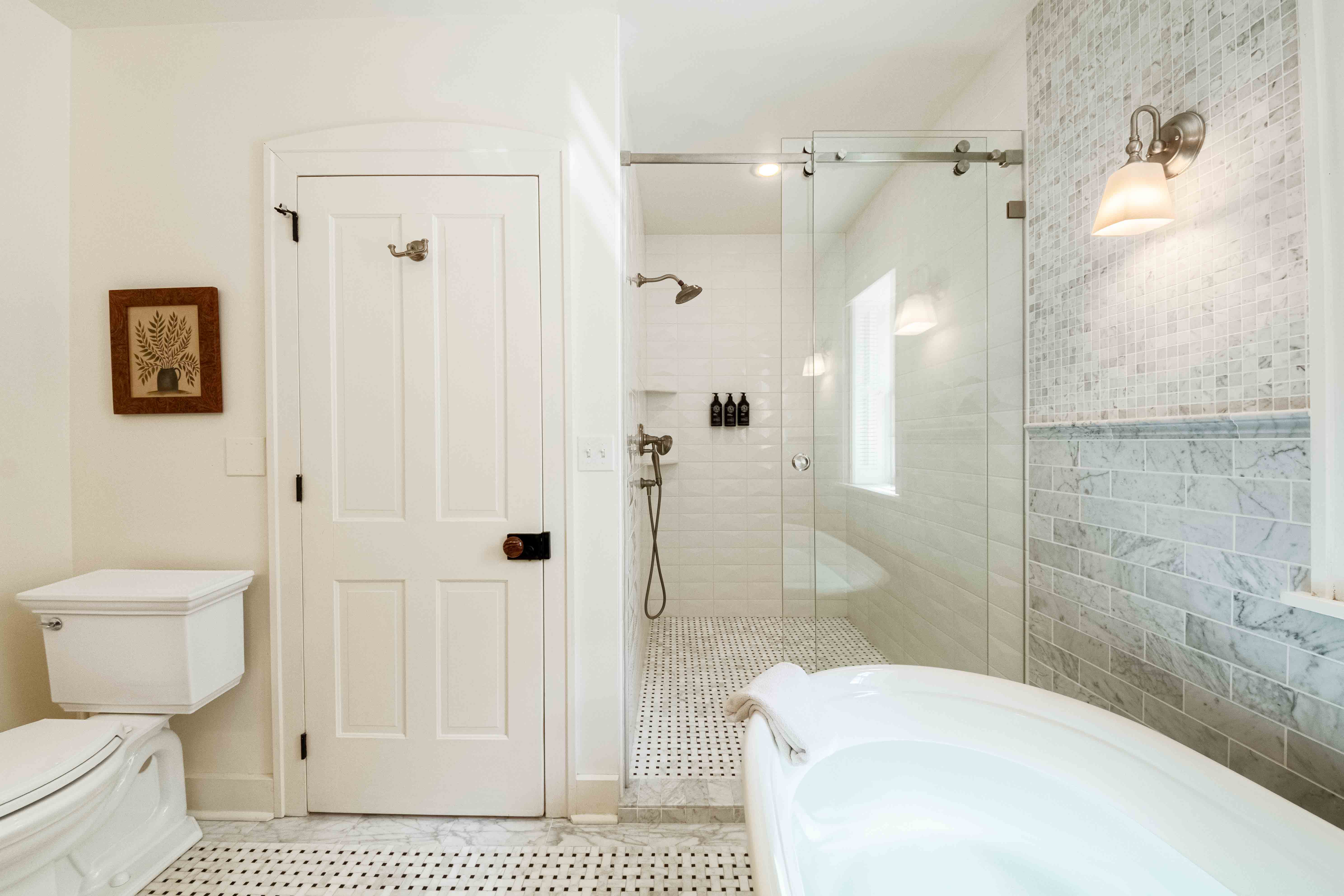 Modern bathroom featuring a glass shower, freestanding tub, and elegant tilework.