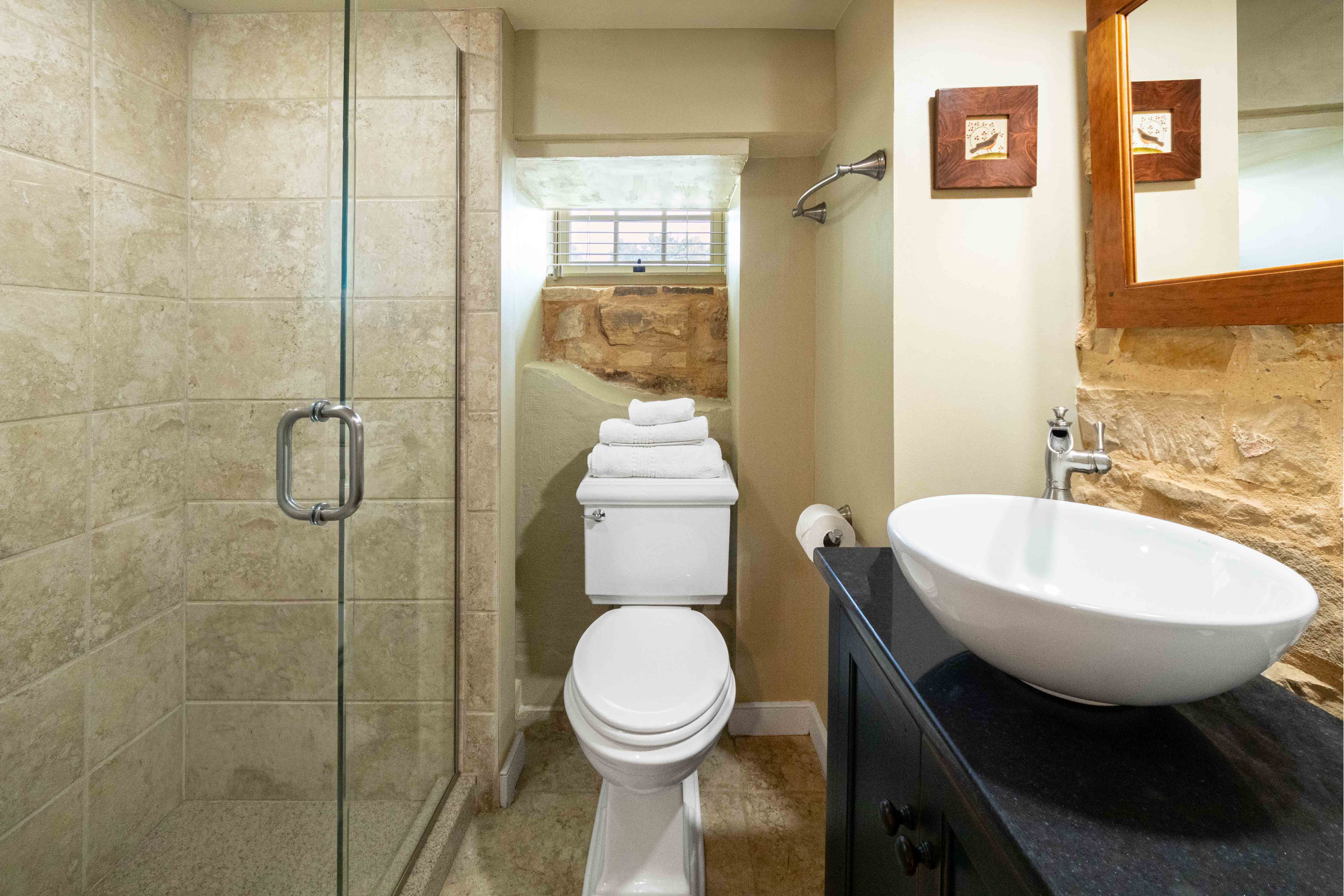 Bathroom featuring a glass shower, compact toilet, and modern sink.