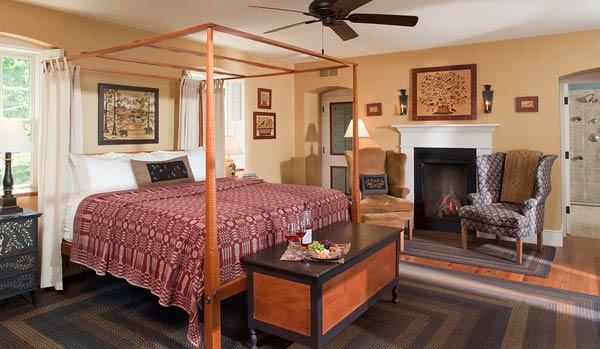 A cozy bedroom featuring a four-poster bed, a fireplace, and comfortable seating.