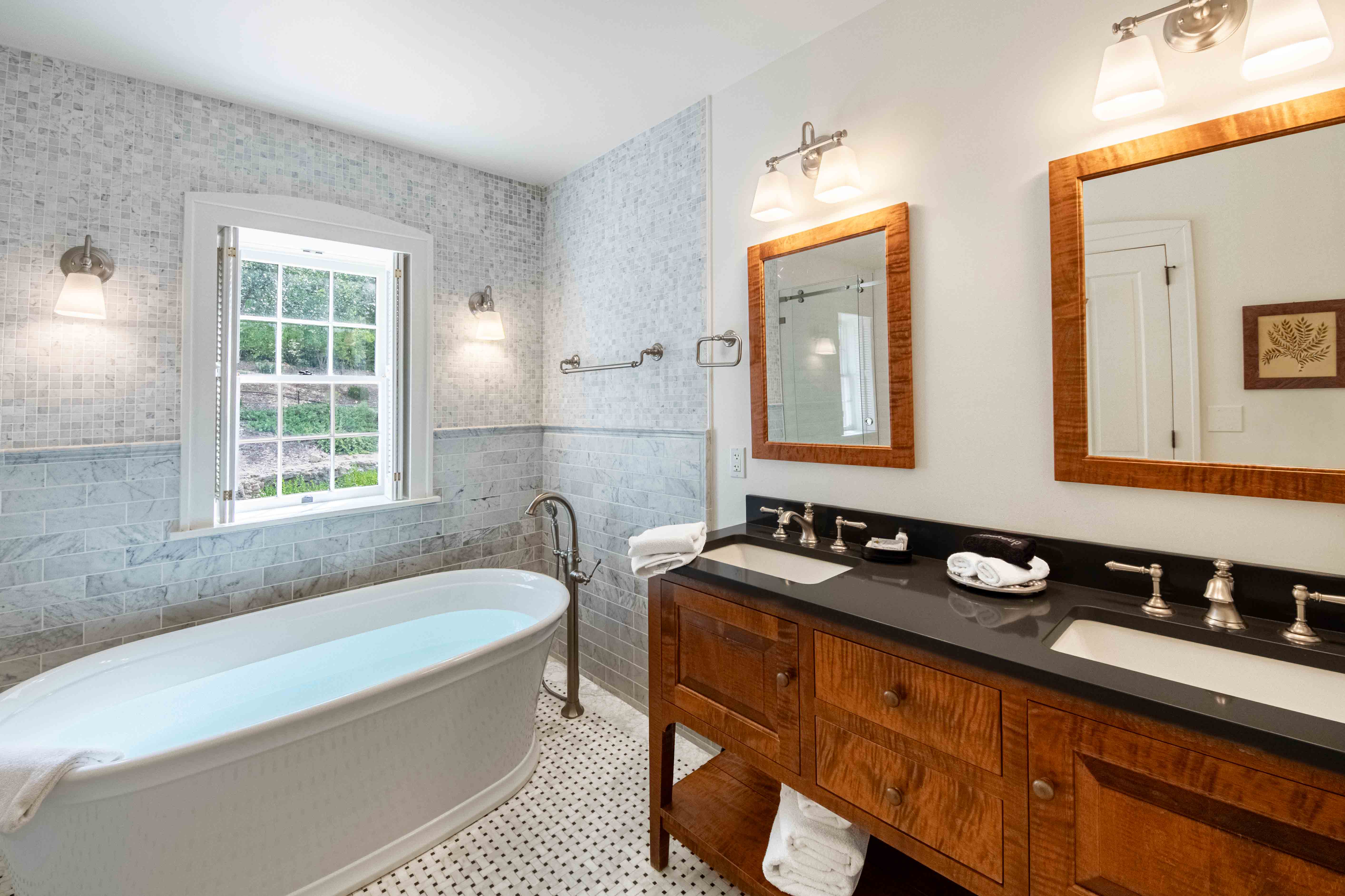 A modern bathroom featuring a freestanding bathtub, double vanity, and large window.